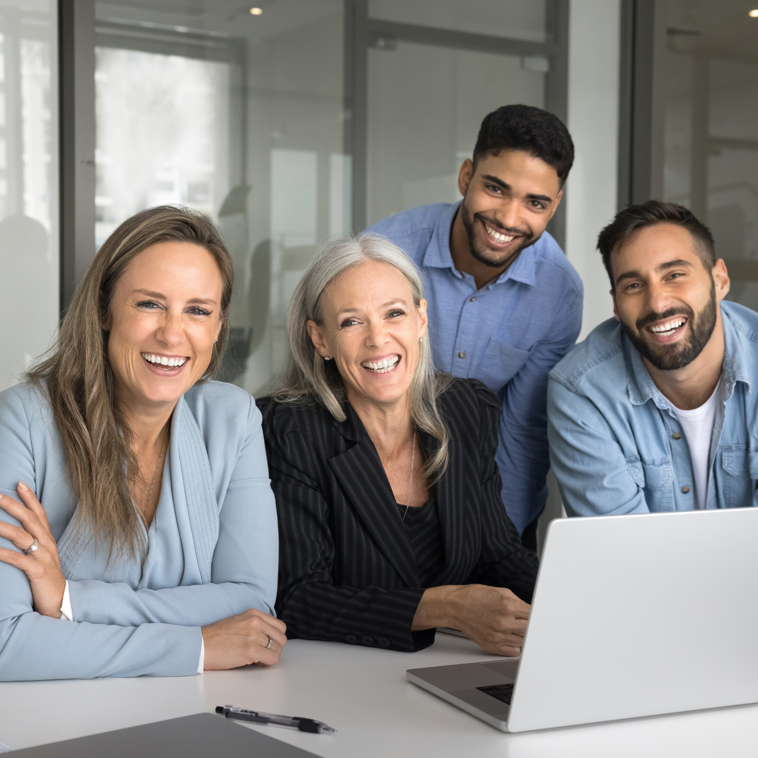 A group of people sitting around a table with a laptop.